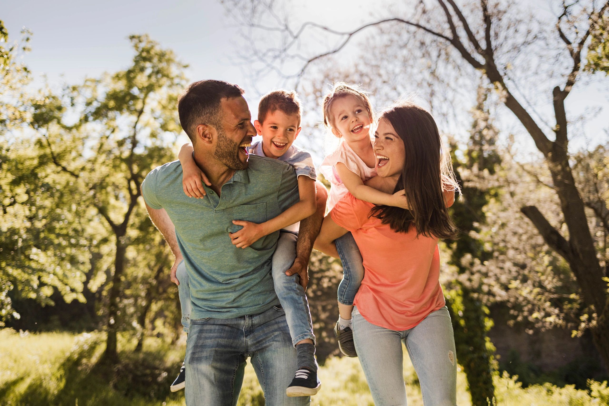 Family piggybacking outdoors in spring